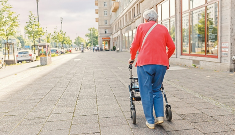 Eenzame vrouw loop over straat achter haar rollator