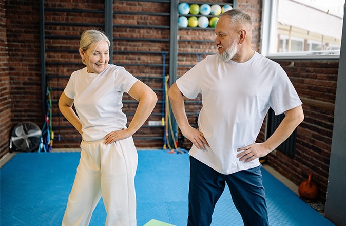 Een oudere man en vrouw doen oefeningen om de klachten van heupartrose te verminderen