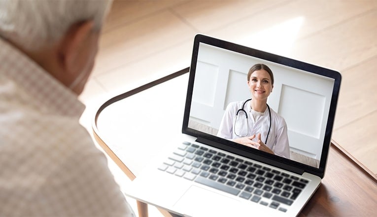 Een oudere man praat dankzij e-health via de laptop met zijn dokter.