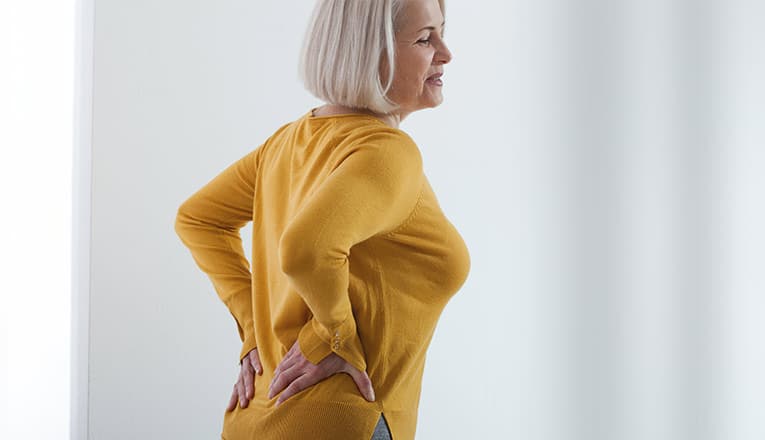 Une femme se plaint de symptômes d'arthrose du dos, tels que des raideurs et de la douleur.