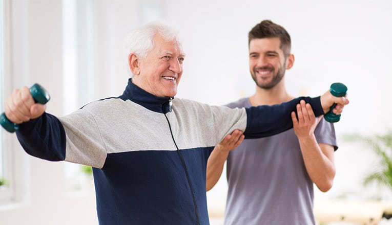 Un vieux monsieur fait des exercices avec un accompagnant.